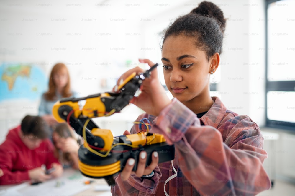 Uma estudante universitária segurando seu brinquedo robótico na sala de aula de robótica da escola.