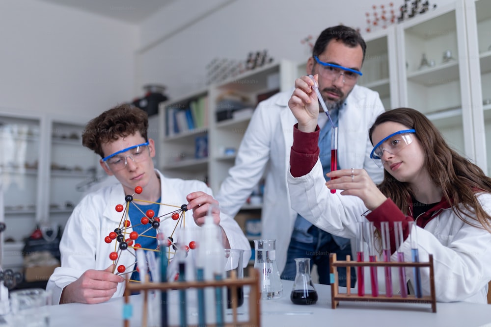 Naturwissenschaftliche Studenten mit einem Lehrer, der chemische Reaktionsexperimente im Labor der Universität durchführt.