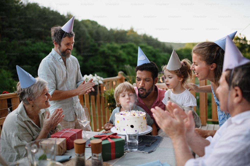 Una famiglia multi generazione che festeggia il compleanno e fa festa in giardino fuori nel cortile sul patio.