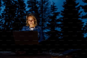 Woman, freelancer working on laptop, sitting outdoor in the evening, concept of remote office, working during vacation.