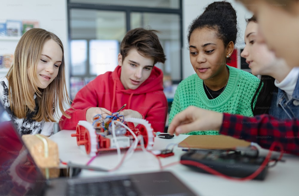 Un gruppo di studenti delle scuole superiori che costruiscono e programmano giocattoli elettrici e robot in un'aula di robotica