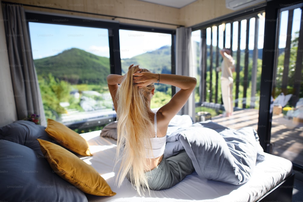 Une vue arrière d’une jeune femme au lit le matin avec son mari sur la terrasse de leur nouvelle maison dans une petite maison, concept de vie durable.