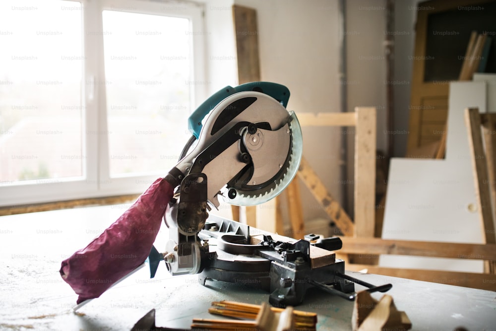 Mitter saw in a carpenter workroom. Electric tool and wooden tape measure on the table.