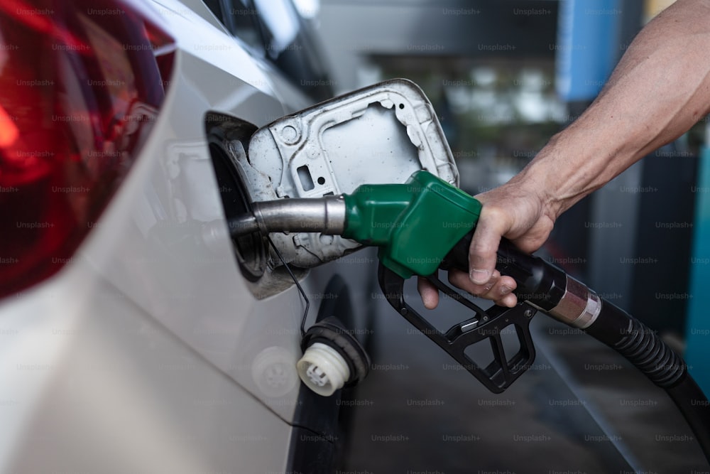 A close-up of worker standing on gas station and fueling car.