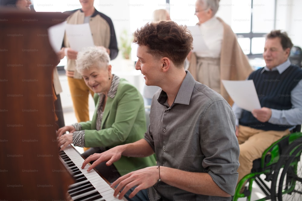 合唱団のリハーサルでピアノを弾く若い先生と年配の女性。