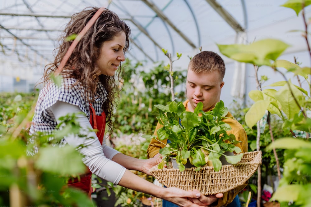 Una fiorista esperta che aiuta una giovane dipendente con sindrome di Down in un centro di giardinaggio.
