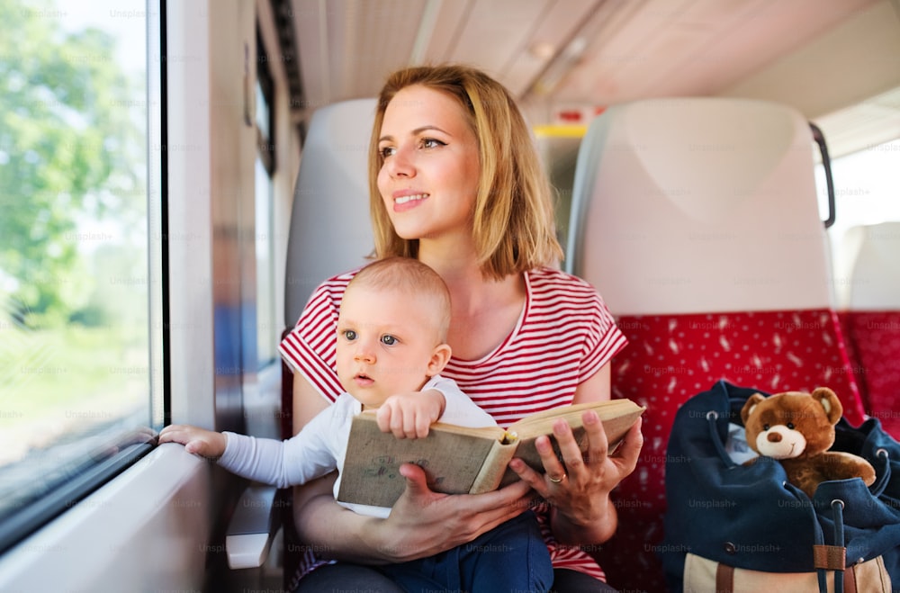 Joven madre que viaja con su bebé en tren. Viaje en tren de una hermosa mujer y su hijo.