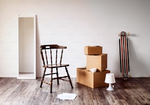 Des boîtes en carton emballées, un miroir, une chaise et d’autres choses dans une maison vide. Emménager dans un nouveau concept de maison.