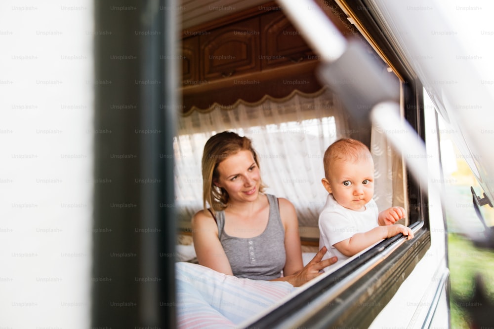 Beautiful young mother and her baby son in a camper van on a summer day