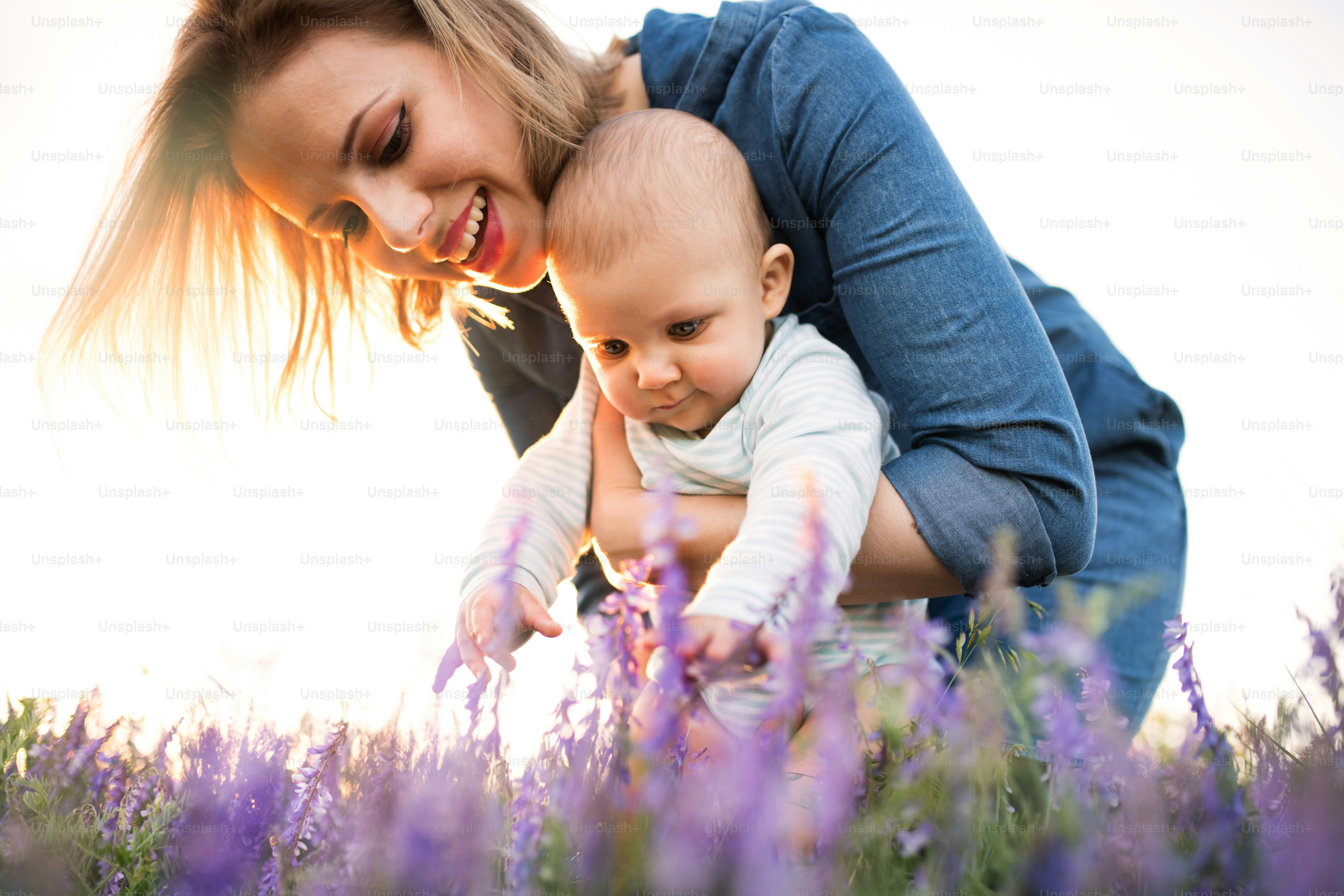 Ibu muda yang cantik menggendong bayi laki-lakinya yang masih kecil di pelukan di luar ruangan di alam di ladang lavender.