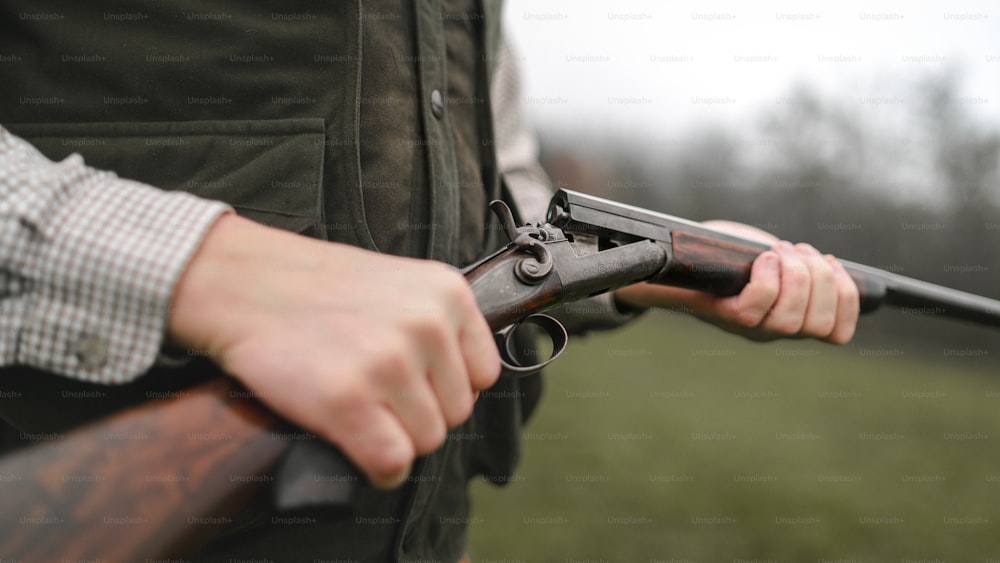 A close-up of hunter man charges the cartridge on rifle gun in forest.