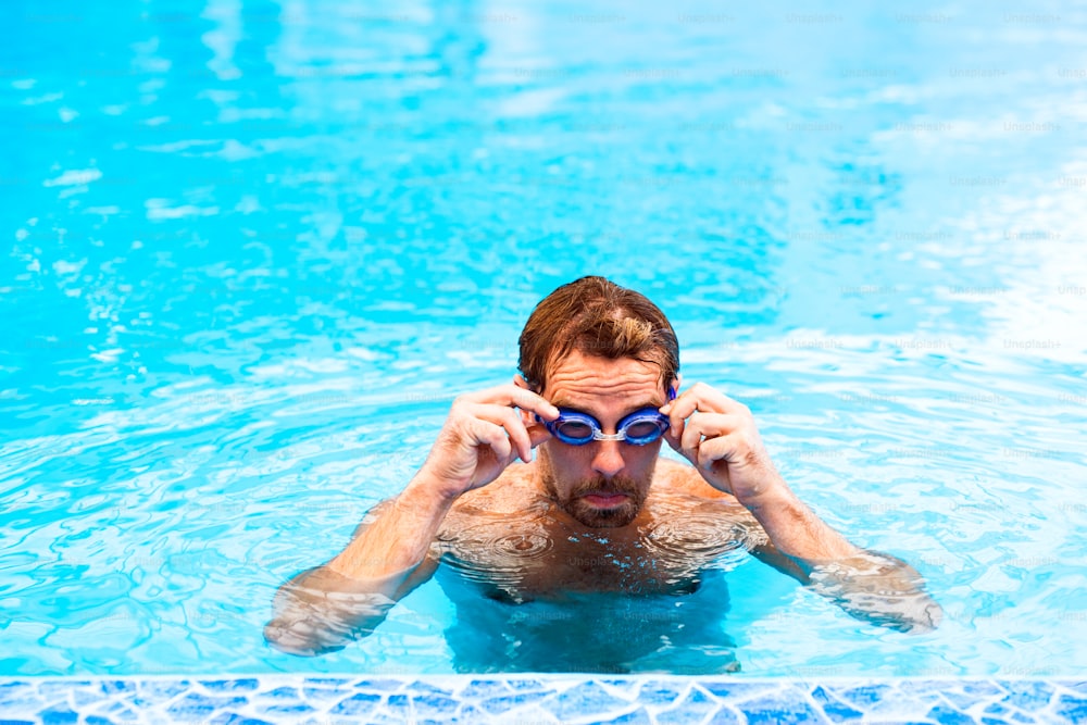 Homem nadando em uma piscina coberta. Nadador profissional que pratica em piscina.