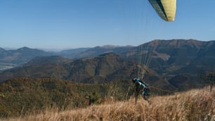 A paraglider landing on the ground against the blue sky.