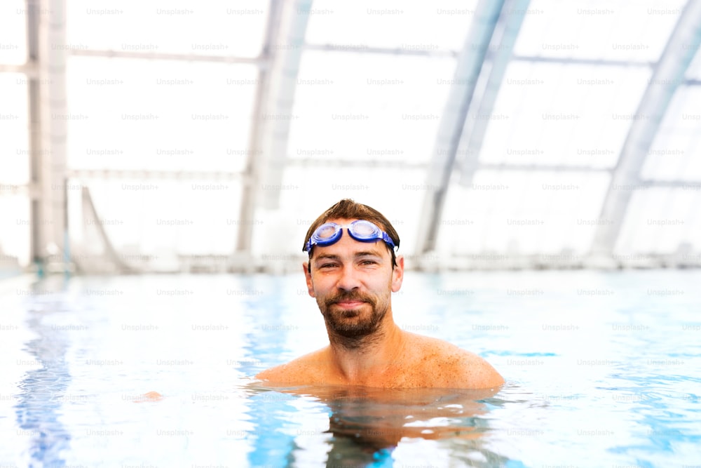 Uomo che nuota in una piscina coperta. Nuotatore professionista che si allena in piscina.