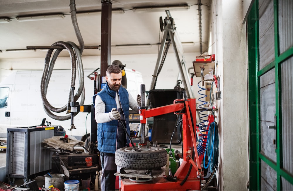 Mature man mechanic repairing a car in a garage.
