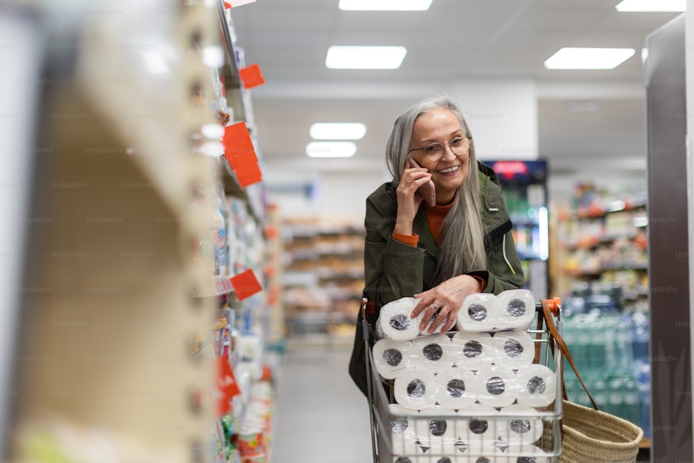 A senior woman buying toliet paper and calling in supermarket.