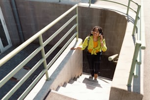 A young biracial woman wearing headphones and enjoying listening to music outdoors in street.