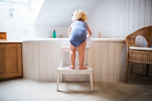 Menino pequeno entrando em uma banheira. Acidente doméstico. Situação perigosa no banheiro. Vista traseira.