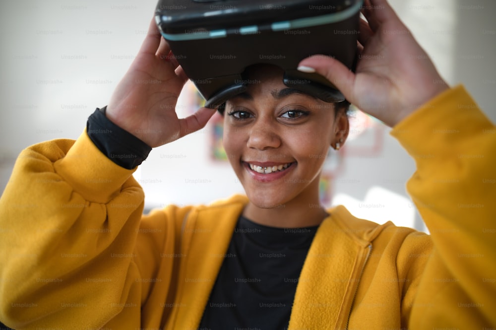 A happy student wearing virtual reality goggles at school in computer science class, looking at camera.