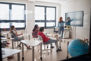 Glücklicher junger Gymnasiallehrer gibt Marketingunterricht für Schüler im Klassenzimmer
