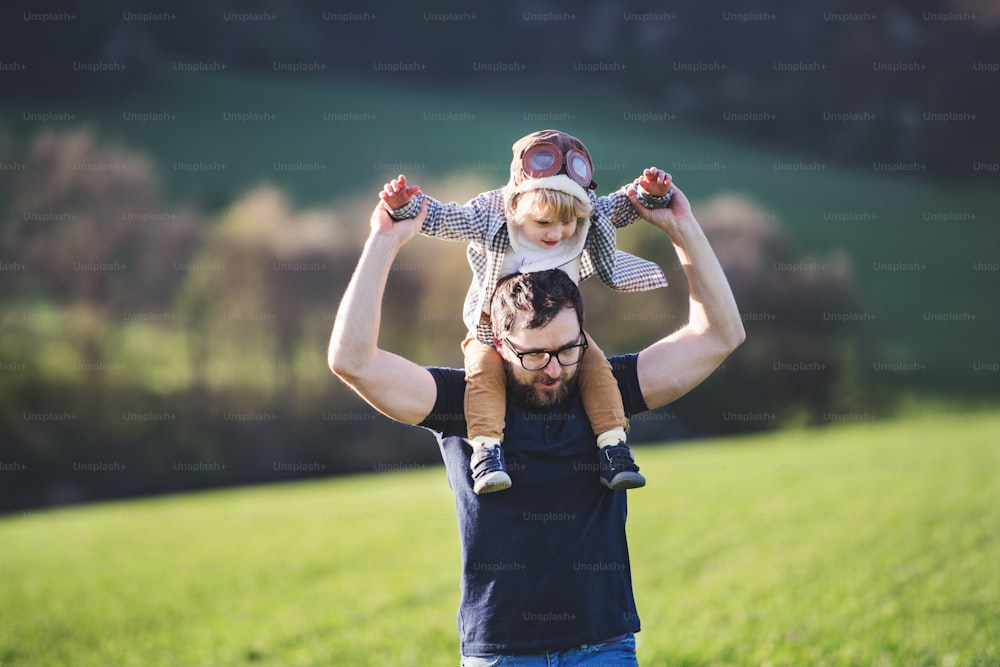 A father with his toddler son outside in green sunny spring nature, having fun.