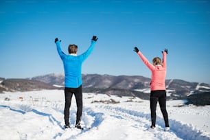 Senior couple jogging outside in winter nature. Rear view.