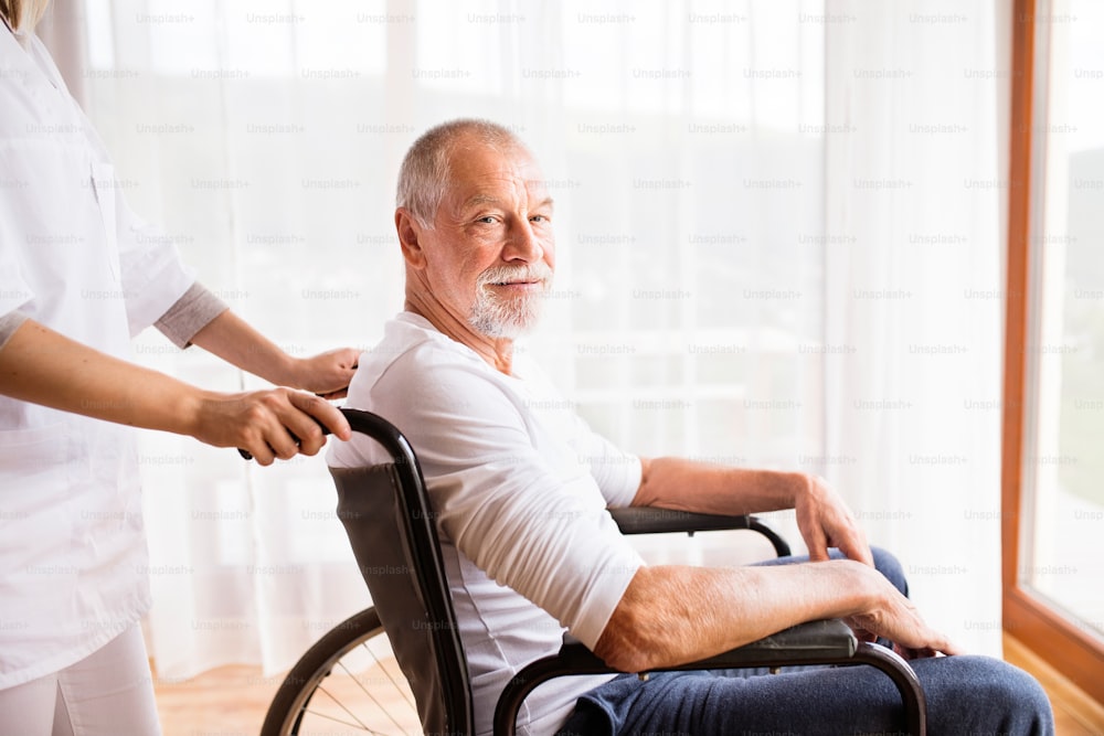 Visiteur de santé méconnaissable ou une infirmière et un homme âgé en fauteuil roulant lors d’une visite à domicile.