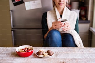 Unrecognizable young woman sitting and drinking coffee.