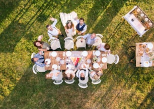 Ricevimento di nozze all'aperto nel cortile. Sposa e sposo con una famiglia in piedi intorno al tavolo, salutando. Veduta aerea.