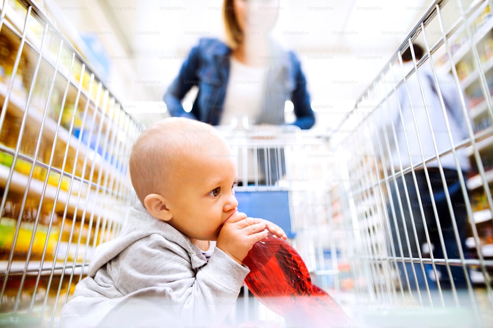 알아볼 수 없는 젊은 엄마가 슈퍼마켓에서 어린 아들과 함께 쇼핑을 하고 있다.
