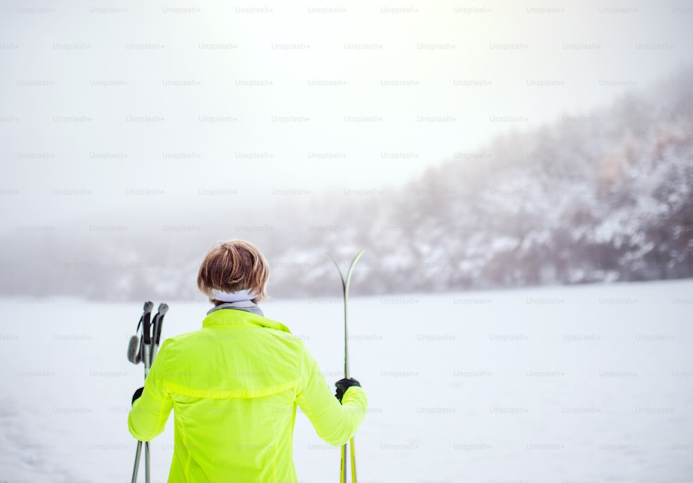 크로스컨트리 스키를 타는 활동적인 시니어 여성. 겨울철. 후면도.