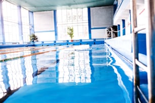 Senior man swimming in an indoor swimming pool. Active pensioner enjoying sport.