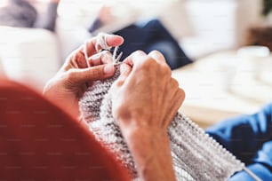 Unrecognizable senior woman relaxing at home, knitting. Close up.