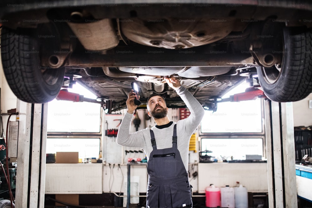 Reifer Mechaniker, der ein Auto in einer Garage repariert.