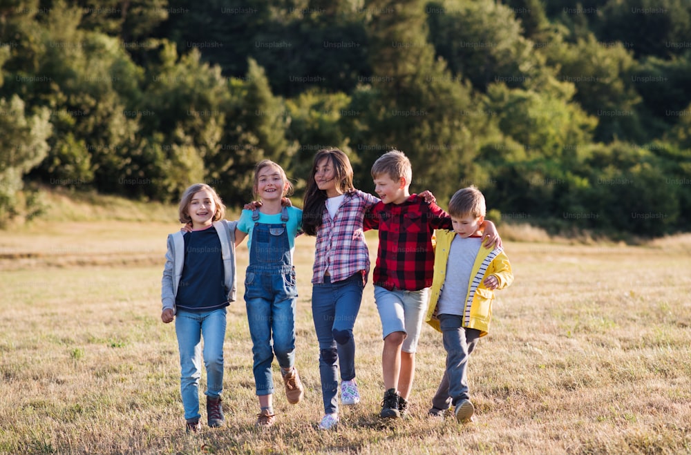 A group of school children walking on field trip in nature, arm in arm.