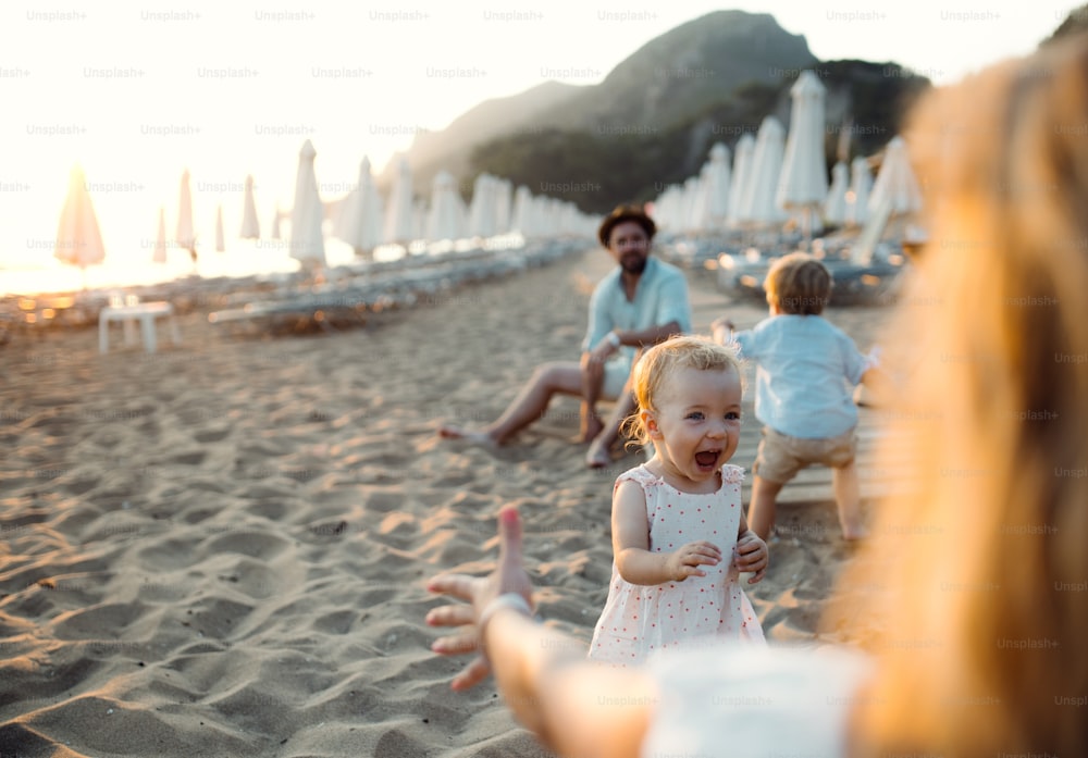 Una familia joven con niños pequeños divirtiéndose en la playa durante las vacaciones de verano. Espacio de copia.