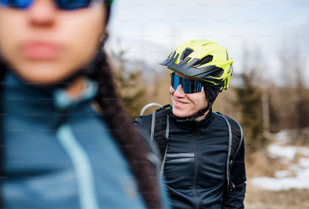 Two mountain bikers standing on road outdoors in winter, resting.