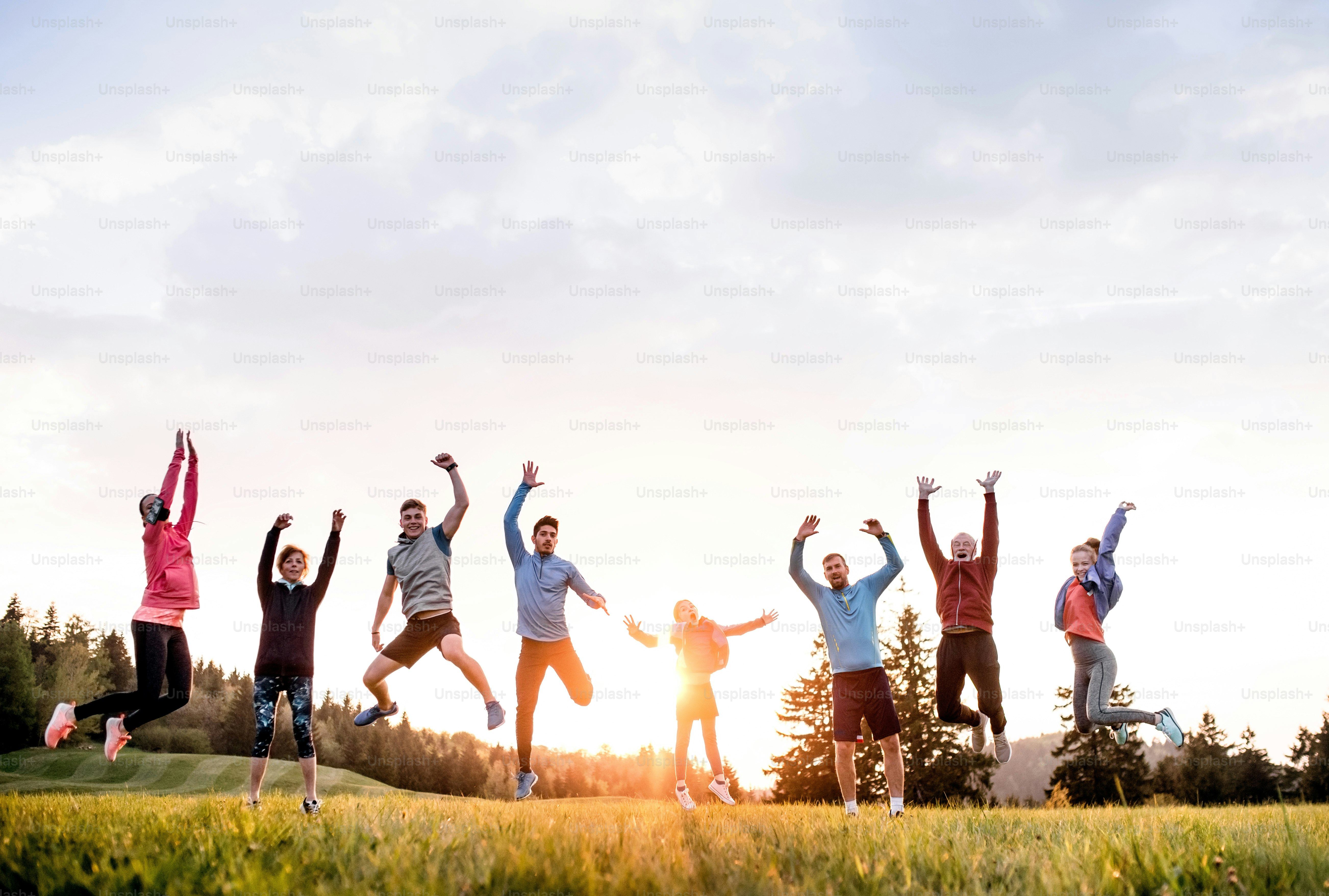 A large group of fit and active people jumping after doing exercise in nature.