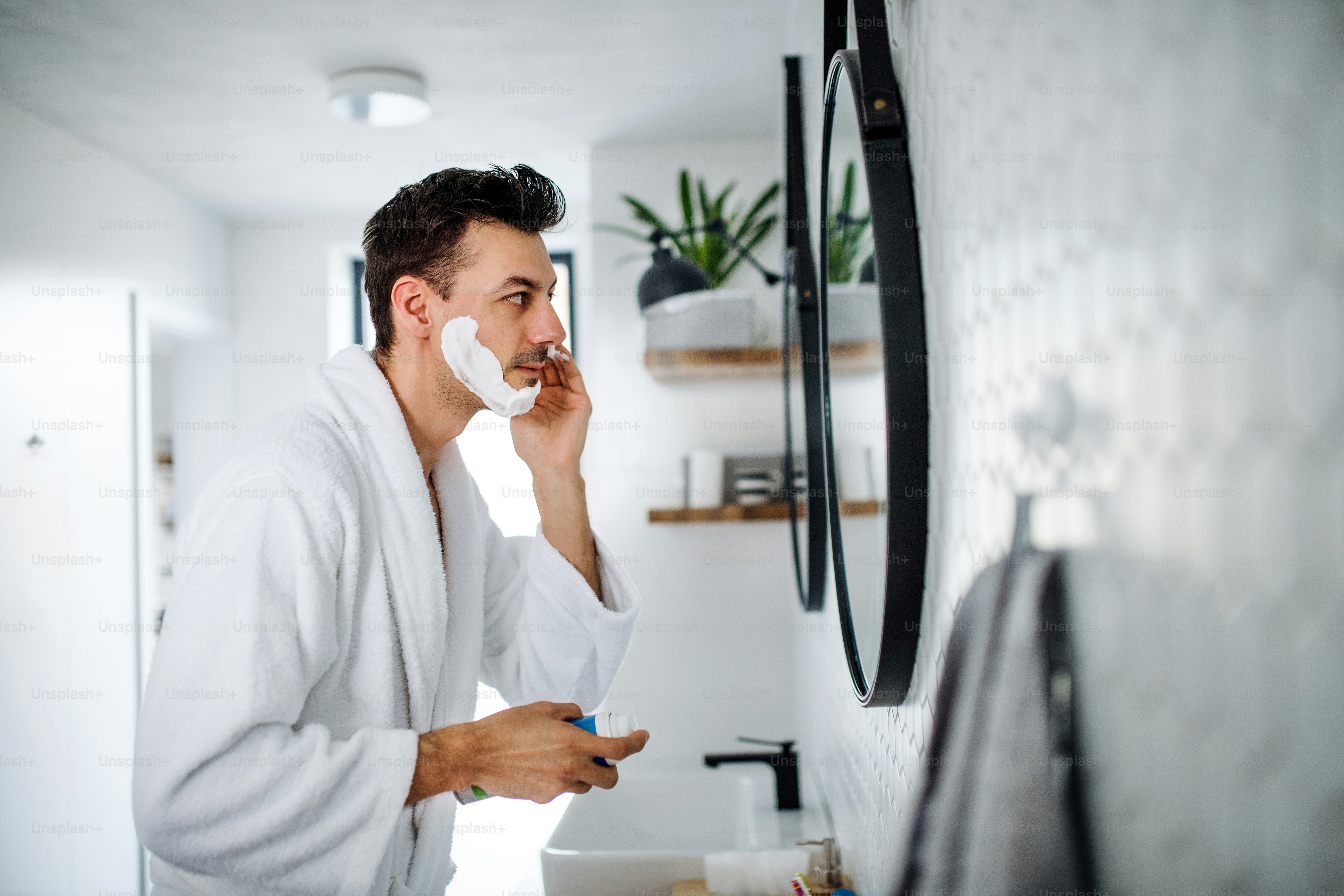 Ein junger Mann rasiert sich morgens im Badezimmer, eine tägliche Routine.