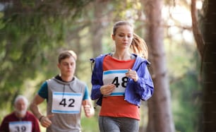 A group of active multi generation people running a race competition in nature.