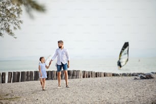A mature father and small daughter on a holiday walking by the lake or sea.