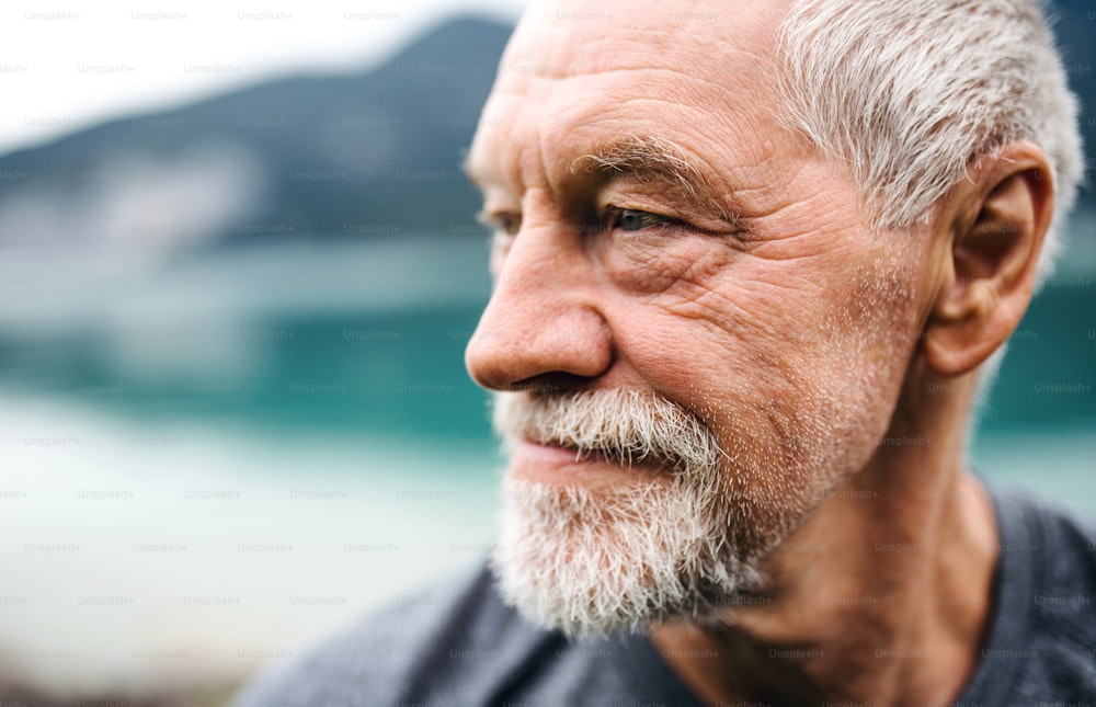 A close-up portrait of senior man pensioner standing outdoors in nature. Copy space.