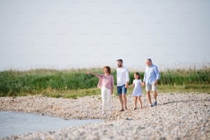 A multi-generation family on a holiday walking by the lake, holding hands.