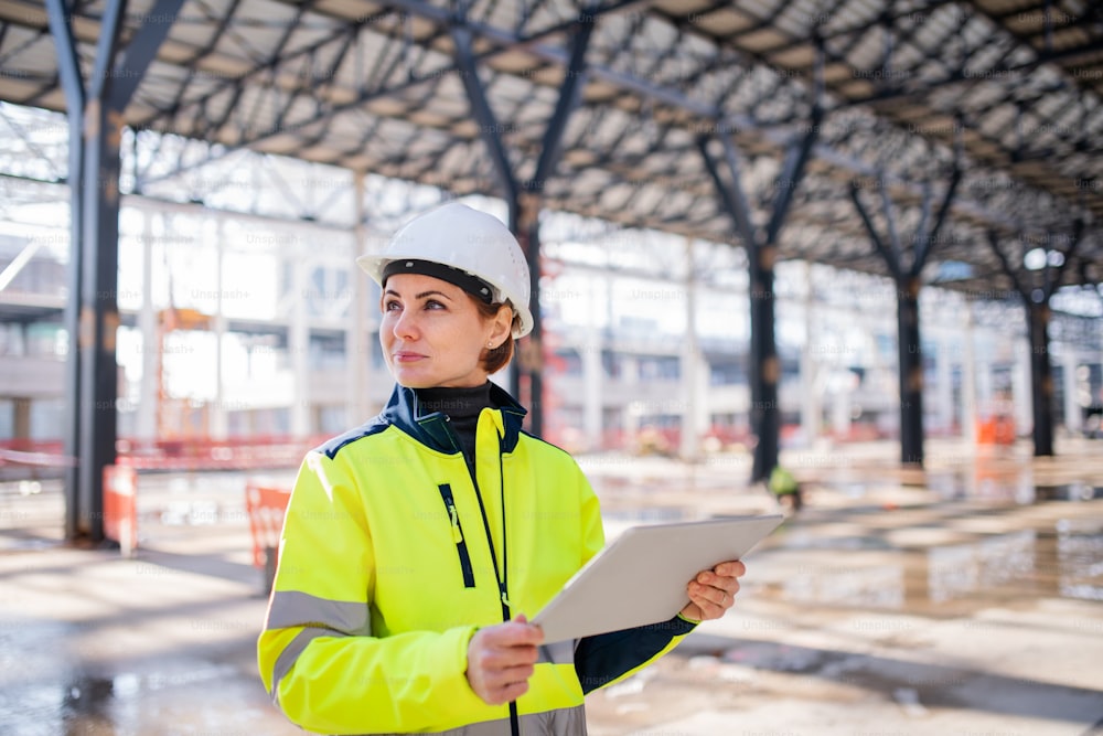 Une femme ingénieure avec une tablette debout sur un chantier de construction, en train de travailler. Espace de copie.