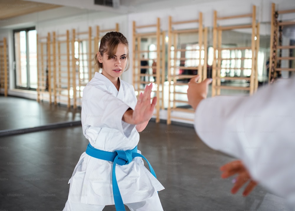 Due giovani donne che praticano karate al chiuso in palestra.