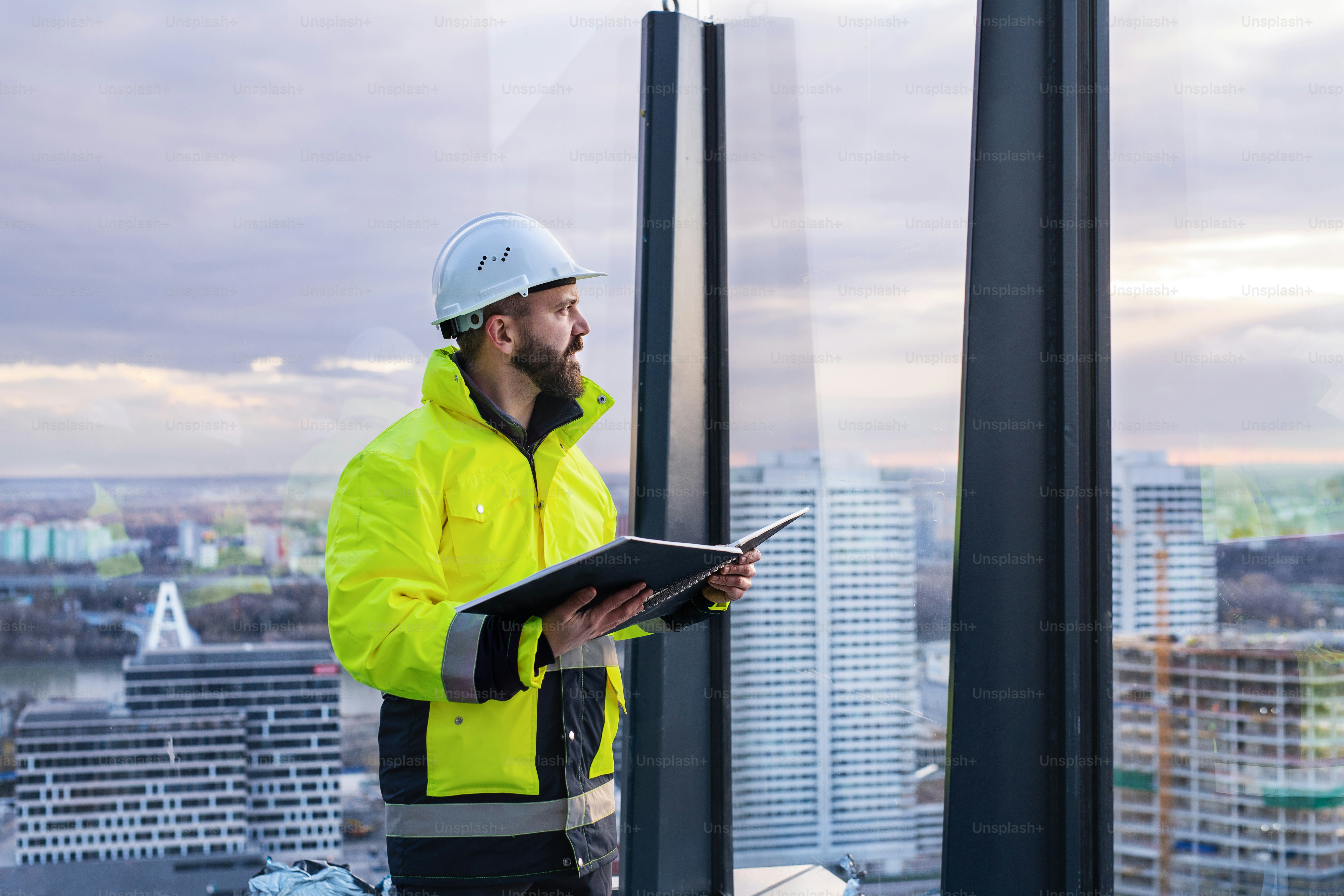 Ingeniero hombre maduro de pie en el sitio de construcción, sosteniendo planos.