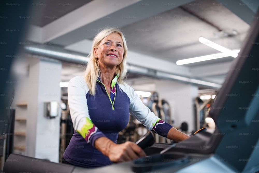 Eine glückliche ältere Frau im Fitnessstudio, die Cardio-Training macht.