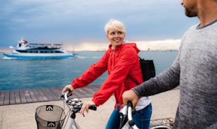 Couple heureux avec des vélos à l’extérieur sur la plage, en train de parler.