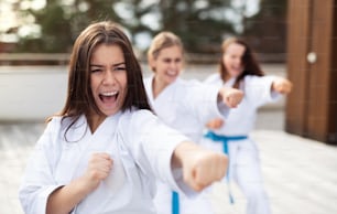 A group of young women practising karate outdoors on terrace.