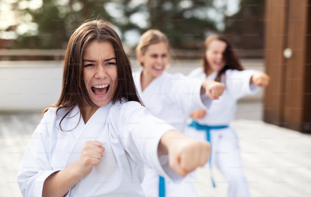 Eine Gruppe junger Frauen übt Karate im Freien auf der Terrasse.